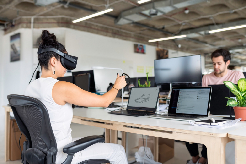 A person with a VR headset in front of a laptop.