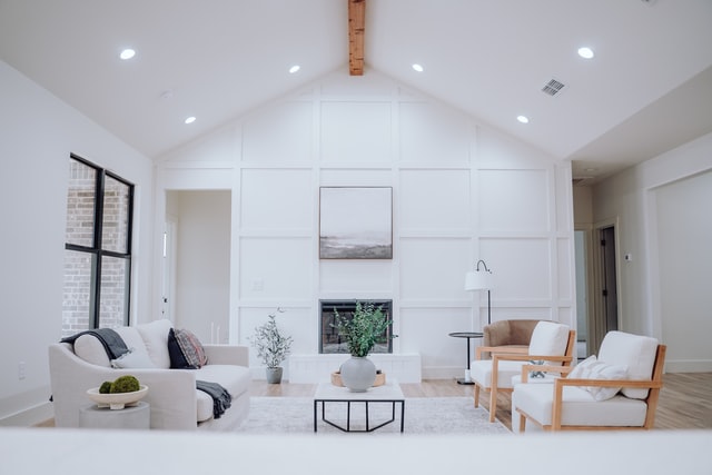 A large living room painted white with white furniture and ceiling lights