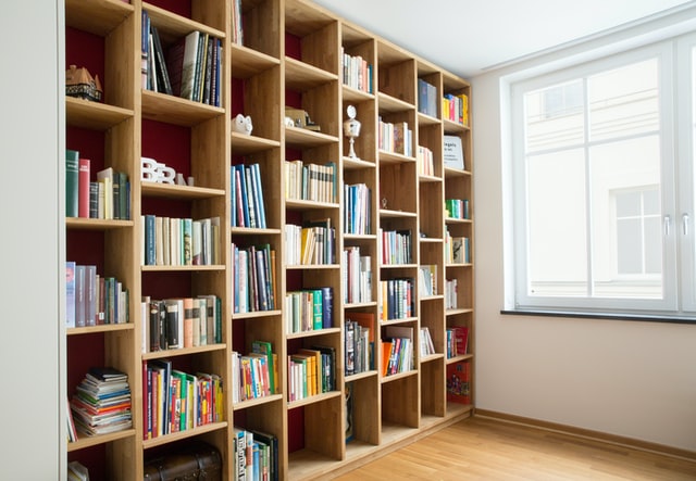 Home library with a large window is one of the ways to use the spare room in your home
