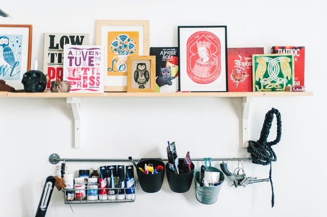 -Colorful wooden frames on a floating shelf in an arts and crafts room