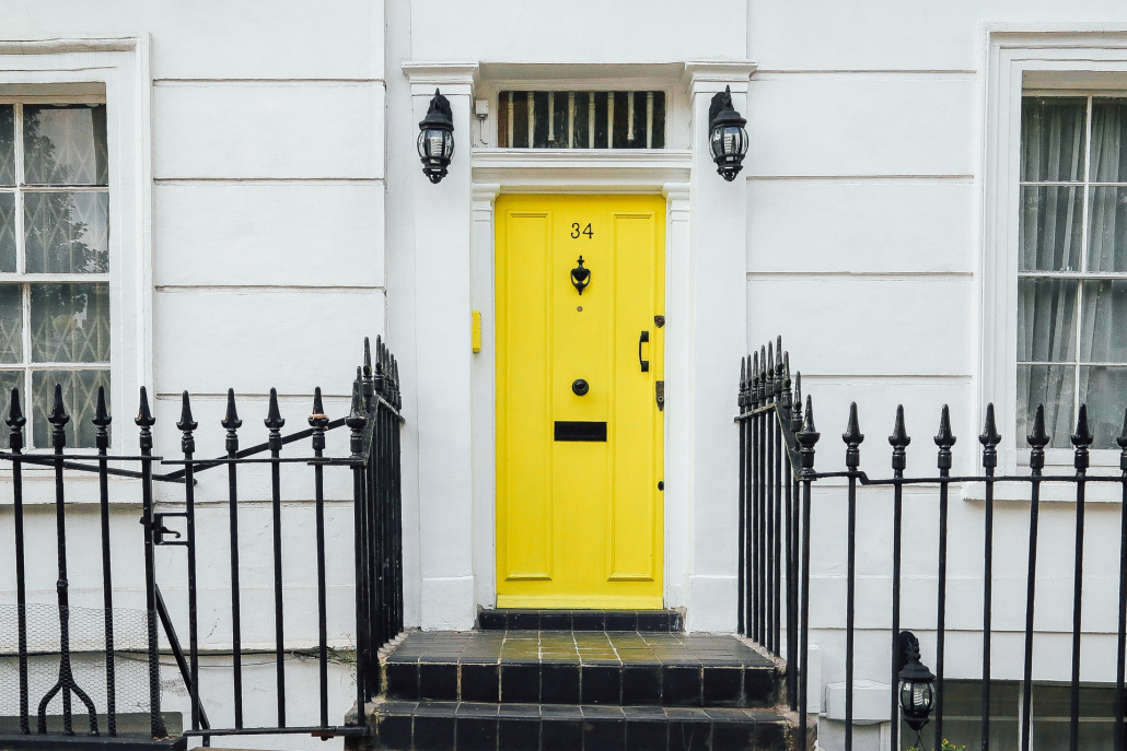 A shining yellow door on a white house.