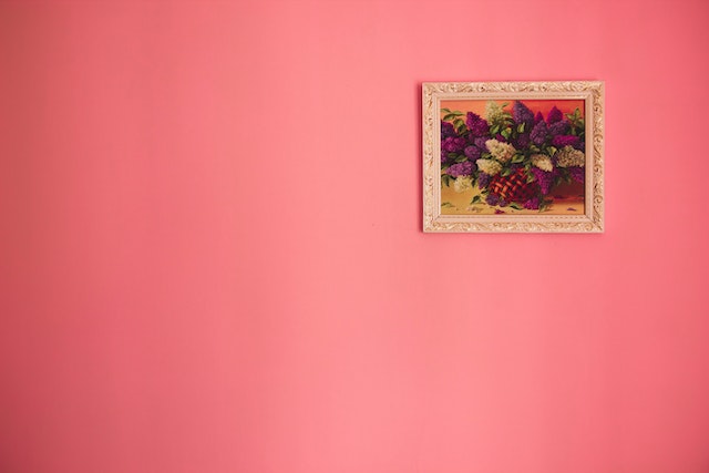 A coral wall with a painting of flowers on it.