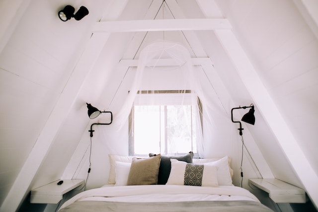 A white bedroom with green details in a small attic.