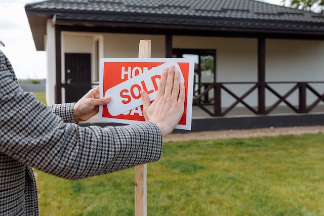 a person putting a sign on a sold house