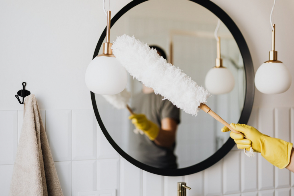 A person cleaning the bathroom mirror