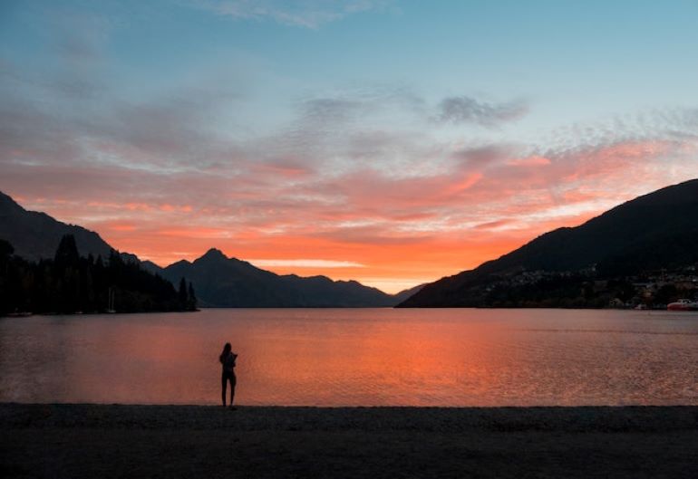 A person at the beach during the sunset. The proximity to the best beaches makes Auckland one of the top-rated places in New Zealand for expat families.