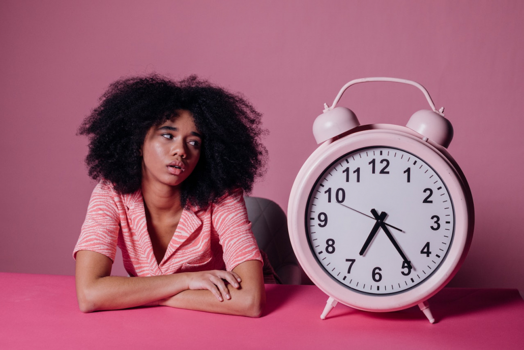 A woman sitting next to a huge clock.