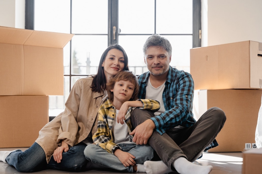 A man, a woman, and a child setting on the floor near packed boxes