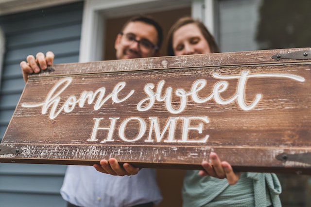 A couple holding a sign “home sweet home” in their hands