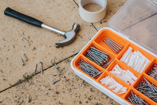 screws and repair tools in a box near a hammer